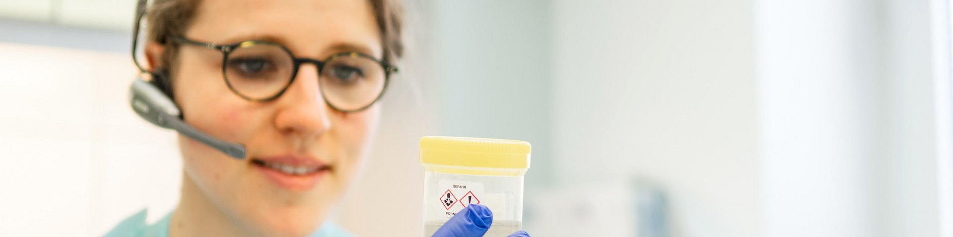 Angestellte schaut sich eine Probe an und telefoniert währendessen über ihr Headset