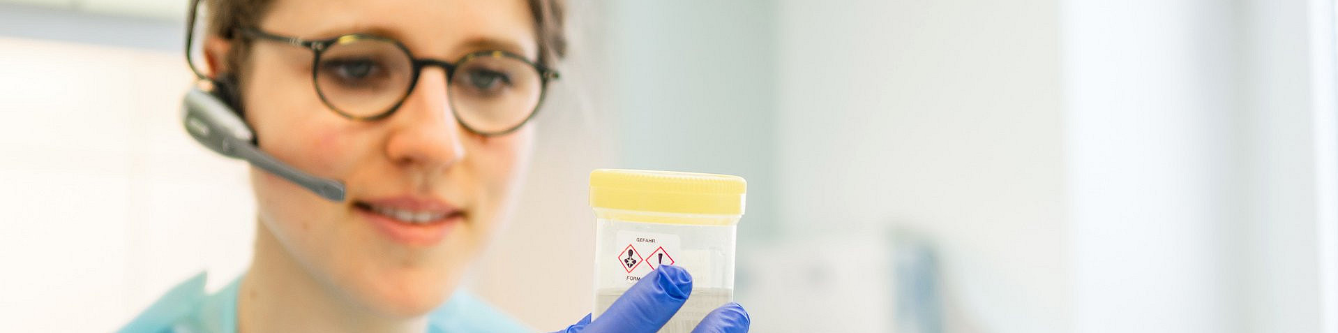 Angestellte schaut sich eine Probe an und telefoniert währendessen über ihr Headset