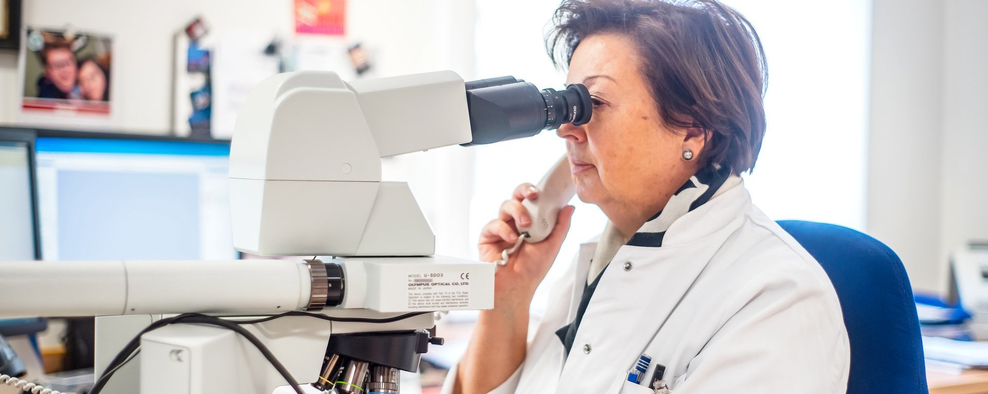 Eine Mitarbeiterin der Pathologie schaut sich eine Probe durch ein Mikroskop an