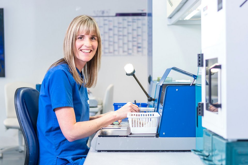 Eine Mitarbeiterin der Pathologie untersucht und wiegt Proben